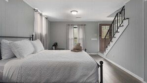 Ein Schlafzimmer mit einem Bett, einem Nachttisch, einer Topfpflanze und einer Treppe.