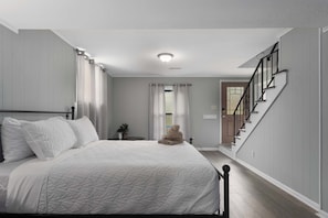 Ein Schlafzimmer mit einem Bett, einem Nachttisch, einer Topfpflanze und einer Treppe.