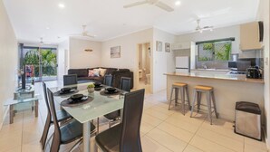 A modern apartment with a dining area, kitchen, and living room. - Tropical Breeze Poolside Stay near the Waterfront (Parap)