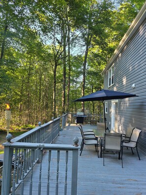 Une terrasse dotée de mobilier d’extérieur, d’un barbecue et d’une rambarde.