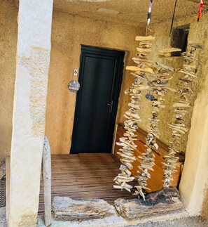 A narrow hallway with a wooden door, a welcome sign, and a wall adorned with driftwood. - Perfect for couples—just a 3-minute walk from Liscia Beach. Pets allowed. (Calcatoggio)