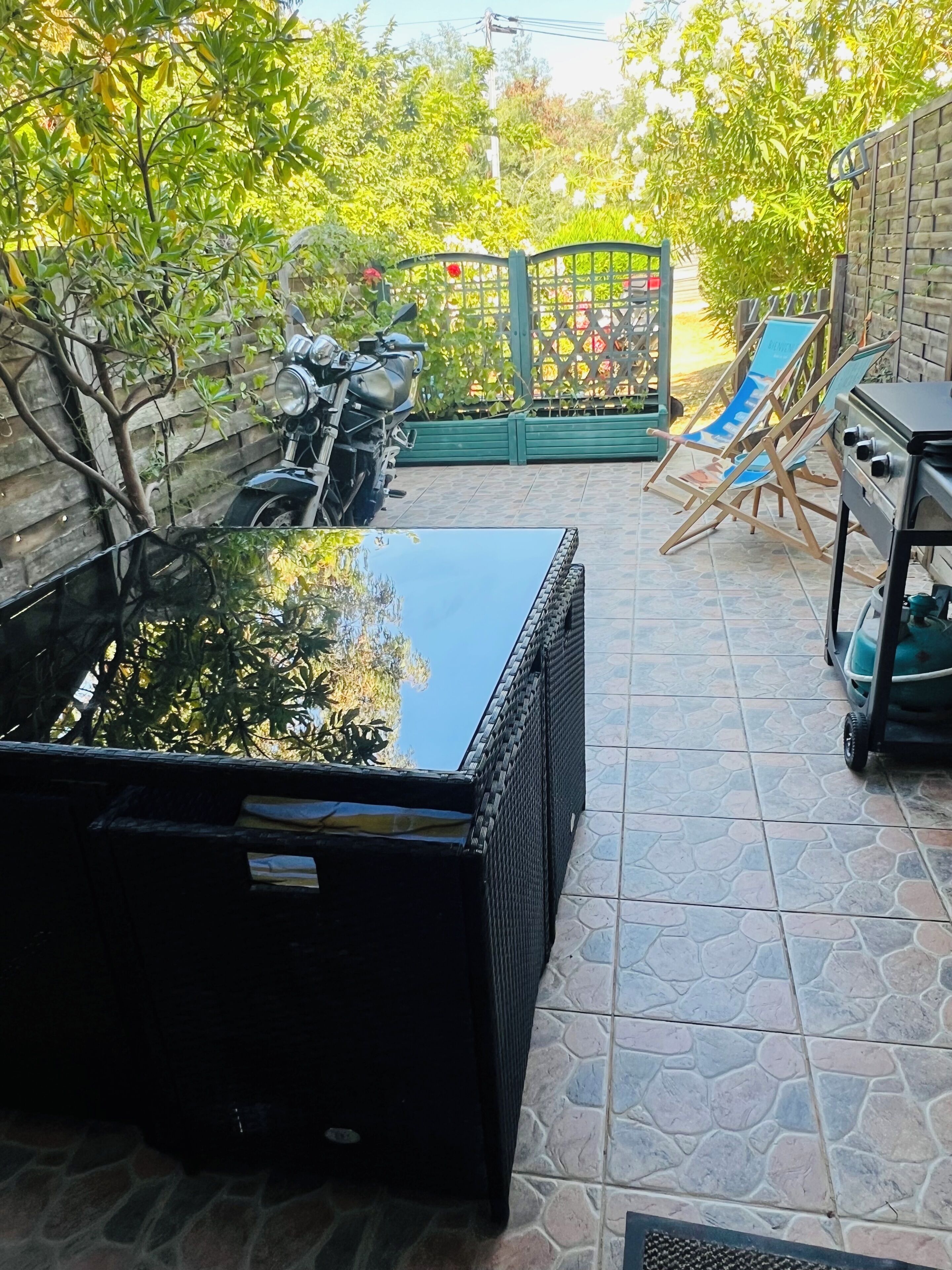 Un espace patio agrémenté d’un bassin d’eau noire, d’une moto et d’un coin barbecue.