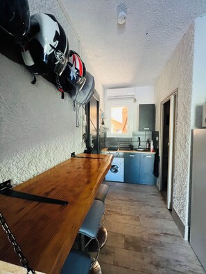 Eine kleine Küche mit Holztisch, Waschmaschine und einem blauen Schrank.