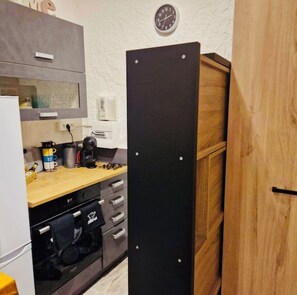 Eine Küche mit einer Holzarbeitsplatte, einem schwarzen Schrank und einer Uhr an der Wand.