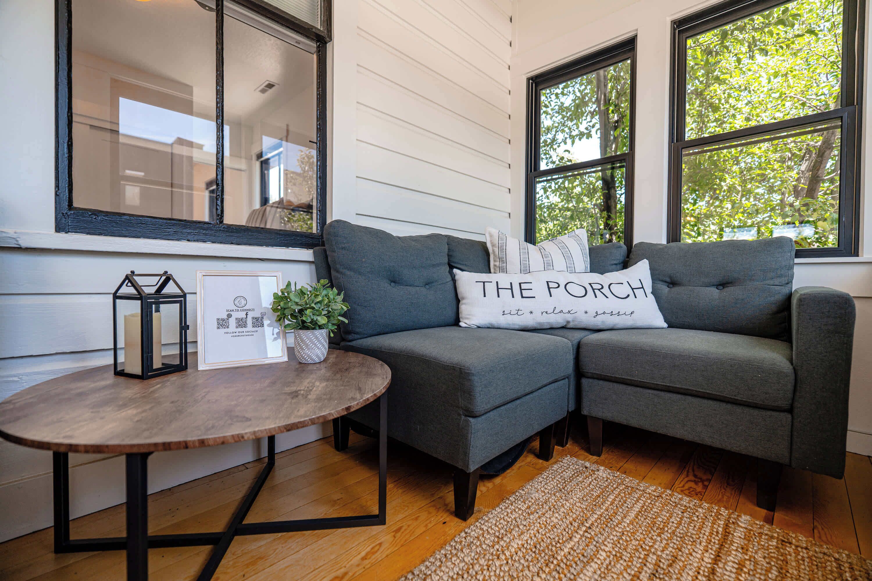 A cozy corner with a gray sofa, a small wooden table, and a potted plant.