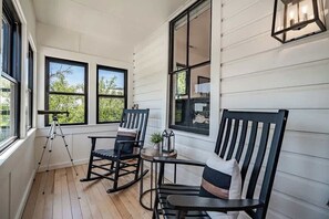 Eine Veranda mit Schaukelstühlen, einem Teleskop und einer Laterne.