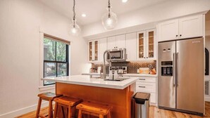 Una cucina moderna con un'isola grande, elettrodomestici in acciaio inossidabile e sgabelli in legno.
