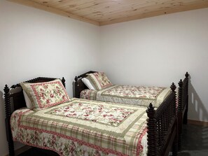 Ein Schlafzimmer mit zwei hölzernen Betten, jeweils mit floralem Bettzeug und einem Holzkopfstück.