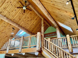 Ein Holzinnenraum mit Balkon, Deckenventilator und Dachfenstern.
