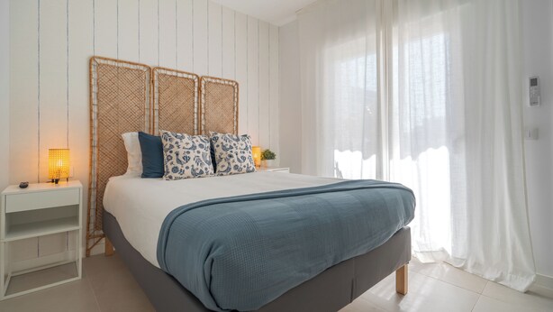 Ein Schlafzimmer mit Bett, Nachttisch und Vorhängen.