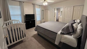 A bedroom with a bed, a crib, a ceiling fan, and a door. - 3-bedroom house, great location. Shopping and dining nearby (El Paso)