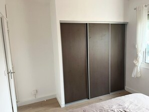A bedroom with a wardrobe, a bed, and a window with curtains. - One-bedroom apartment in Carnon, a 1-minute walk from the beach (Mauguio)