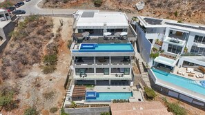Un hôtel à plusieurs étages doté d’une piscine sur le toit, d’un balcon au deuxième étage et d’une terrasse au troisième étage.