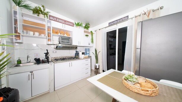 Eine moderne Küche mit weißen Schränken, einem eingebauten Backofen und einem Essbereich mit Tisch und Stühlen.