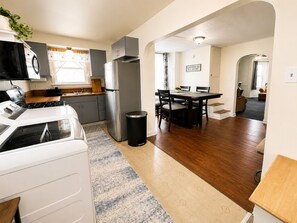 Eine moderne Küche mit Herd, Kühlschrank und Essbereich mit Stühlen und Tisch.