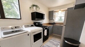 A kitchen with a washer, dryer, stove, microwave, and refrigerator.