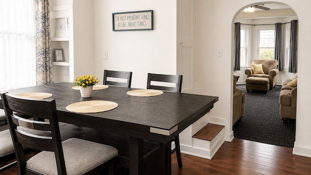 A dining area with a dark wooden table, four chairs, and a potted plant.