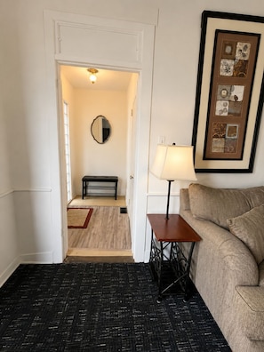 A hallway with a bench, a framed artwork, a lamp, and a sofa.