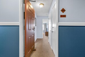 A hallway with a wooden door, a blue wall, and a carpeted floor. - One-Bedroom Suite With Kitchen & Pool and Hot Tub! (Ocean Shores)