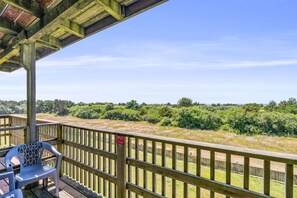 A wooden deck with a view of a grassy field and trees. - Ocean View Family Suite for 6 - Pool and Hot Tub! (Ocean Shores)