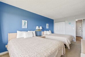 A hotel room with two beds, a nightstand with lamps, and a door leading to another room. - Ocean View Family Suite for 6 - Pool and Hot Tub! (Ocean Shores)