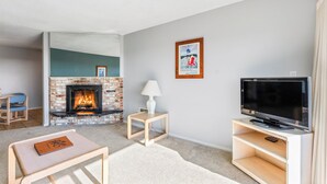 Un salon avec une cheminée, un téléviseur et une petite table sur laquelle se trouve un livre.