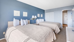 A hotel room with two beds, a nightstand, a lamp, and a door leading to another room. - Ocean View, Pet-Friendly Family Suite with Kitchen - Pool and Hot Tub (Ocean Shores)