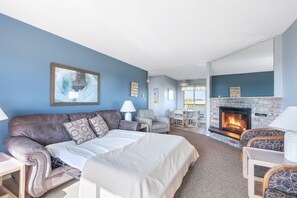 Ein Zimmer mit einem Bett, einem Schlafsofa, einem Kamin und einem Essbereich.