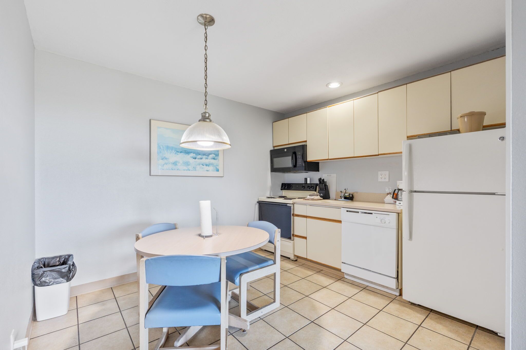 Una cocina compacta con comedor, microondas, estufa, lavavajillas y refrigerador.