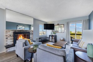 Un salon avec une cheminée, des canapés, un téléviseur et un balcon offrant une vue agréable.