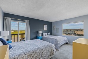 Un dormitorio con dos camas, una ventana con vistas, un balcón y un escritorio.
