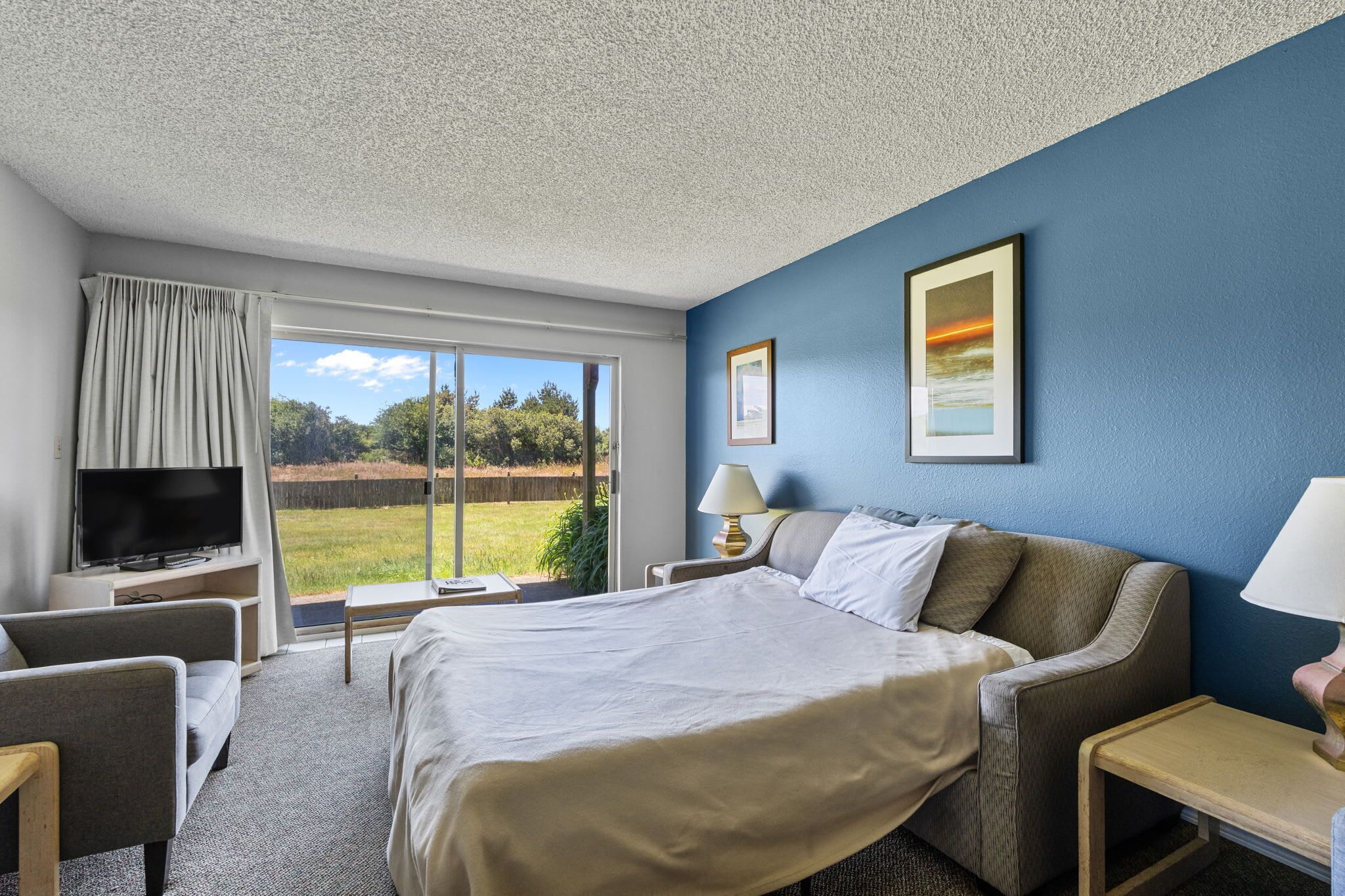 A hotel room with a bed, a TV, a desk, and a chair.
