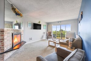 A living room with a fireplace, a sofa, a coffee table, and a TV mounted on the wall. - 1st Floor Family Suite With Pool & Hot Tub Access! (Ocean Shores)