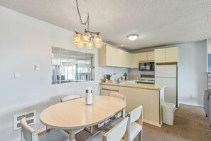 Une cuisine moderne dotée d’un îlot central, d’une table à manger avec des chaises et d’un lustre.
