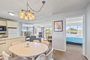 A modern kitchen with a dining area, a pool view, and a large window. - 2-Bedroom Family Suite With King Bed and Kitchen (Ocean Shores)