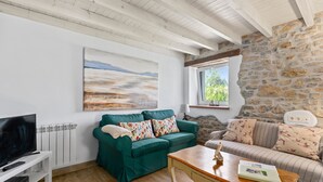 A living room with a television, two sofas, a coffee table, and a stone wall.