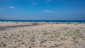 A beach with rocky terrain, a sandy area, and the ocean in the background.