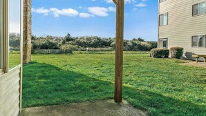 A residential backyard with a stone pillar, a wooden pergola, a lawn, and a house with a light-colored exterior. - Pet-Friendly 2-Bedroom Family Suite With Fireplace (Ocean Shores)