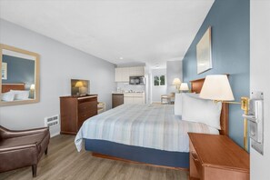 Une chambre d’hôtel comprenant un lit, un bureau, une chaise, une commode et une kitchenette.