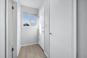 A hallway with a window, a door, and a light switch on the wall. - Pet-Friendly Studio with Kitchenette & Pool Access (Ocean Shores)