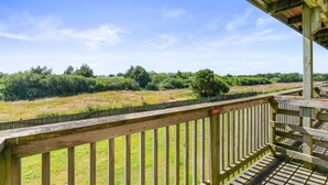 Een houten terras met uitzicht op een grasveld en bomen.