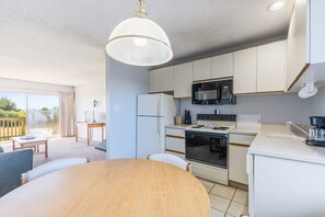 Une cuisine moderne avec des meubles blancs, un four à micro-ondes, une cuisinière et un coin repas comprenant une table et des chaises en bois.