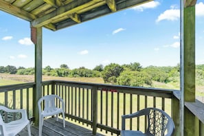A wooden deck with two white plastic chairs, a wooden railing, and a view of a green landscape. - Pet-Friendly Family Fireplace Suite - Kitchen - Pool and Hot Tub! (Ocean Shores)