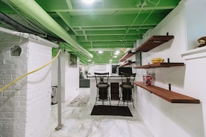 Un pasillo estrecho con pared de ladrillo blanco, techo verde y estante de madera con objetos.