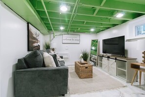 Un salon moderne avec un canapé gris, un téléviseur et un plafond vert.