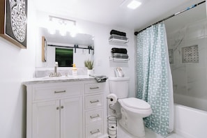 Un baño con inodoro, lavabo, espejo, toallero y cortina de ducha.