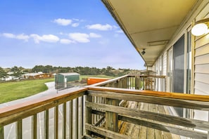 A wooden balcony with a view of a green field and buildings in the distance. - Family Suite for 6 with Fireplace and Kitchen - Pool and Hot Tub! (Ocean Shores)