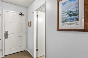 Ein Flur mit einer weißen Tür, einem gerahmten Bild an der Wand und einem Teppichboden.