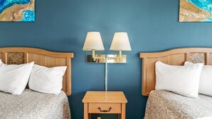 Ein Hotelzimmer mit zwei Betten, einem Nachttisch mit Lampe und Bildern an den Wänden.