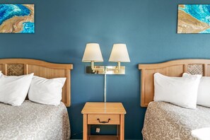 A hotel room with two beds, a nightstand with a lamp, and artwork on the walls. - Pet-Friendly Suite With Pool and Spa Access! (Ocean Shores)